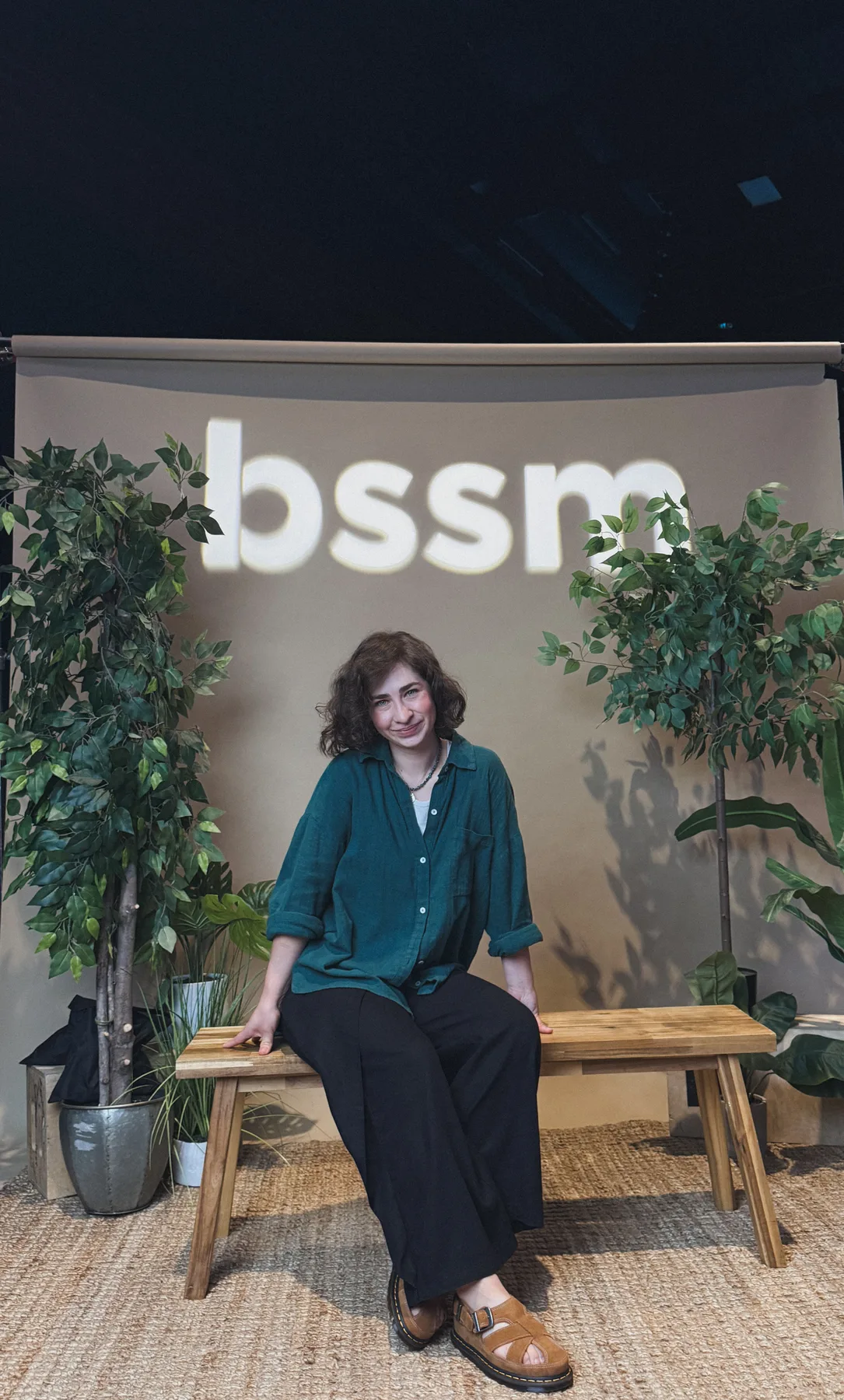 Portrait of Vera seated beneath a BSSM sign in Redding, California.